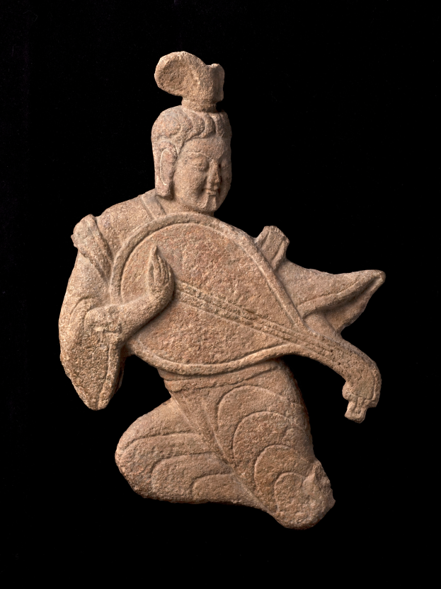 Eine steinerne Skulptur eines Mannes in einem langen Gewand, der ein Musikinstrument spielt und dabei einen friedlichen Ausdruck und geschlossene Augen hat, vor einem schwarzen Hintergrund.