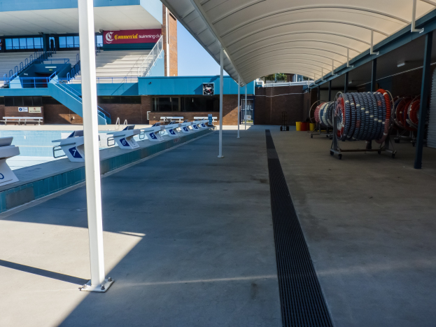 Großer Hallenbad mit zahlreichen Stühlen auf der rechten Seite, einem Gebäude im Hintergrund, verstreuten Gegenständen auf dem Boden und mehreren Pfählen auf der linken Seite an der University of Texas at Austin.