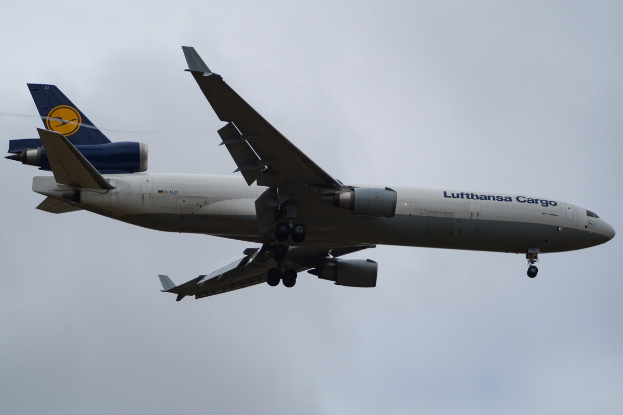Ein Lufthansa Cargo Boeing 777-300ER-Flugzeug im Flug, mit sichtbarem Text auf der Seite, das durch einen Himmel mit weißen, flauschigen Wolken fliegt.