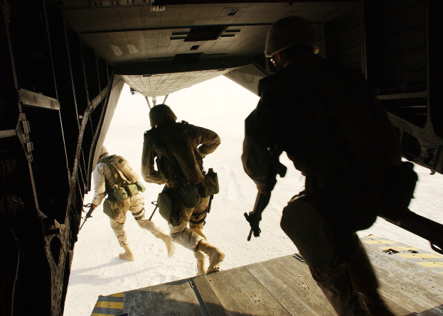 Soldaten in Uniform und Helmen steigen aus einem Flugzeug und halten Gewehre während einer Mission.