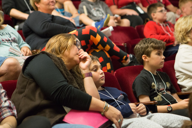 Eine Gruppe von Menschen sitzt in einem Kino, darunter eine Frau und ein Junge.