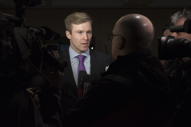 Ein Mann im Anzug mit Brille spricht in ein Mikrofon, während zwei Kameramänner ihn aufnehmen.