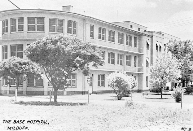 Ein Schwarz-Weiß-Foto des Basis-Krankenhauses in Mildura mit verschiedenen Gegenständen und Himmel im Hintergrund sowie Text unten.