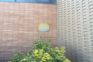 Ein Ziegelgebäude mit einem Strahlensymbol-Schild, einer Pflanze am Boden und einer Tafel an der Wand, die darauf hinweist, dass es sich um ein Kernkraftwerk handelt.