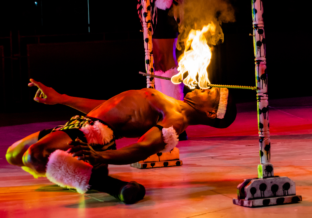 Eine Person schaut auf ein Feuer, das auf einer Stange an Pfählen befestigt ist.