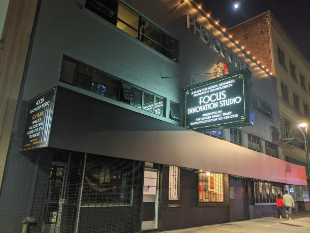 Außenansicht des Focus Innovation Studio in New York City bei Nacht, mit beleuchteten Gebäuden, Menschen auf dem Gehweg und einem sichtbaren Nachthimmel.