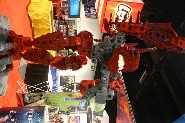 Ein Roboter steht in der Mitte eines Raumes mit Boxen im Hintergrund, Teppich auf dem Boden und einer Decke darüber.