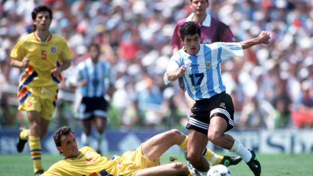 Diego Maradona von Argentinien wird von Diego Sanchez aus Kolumbien getackelt während eines Fußballspiels, mit anderen Spielern, Zuschauern und Plakaten im Hintergrund.
