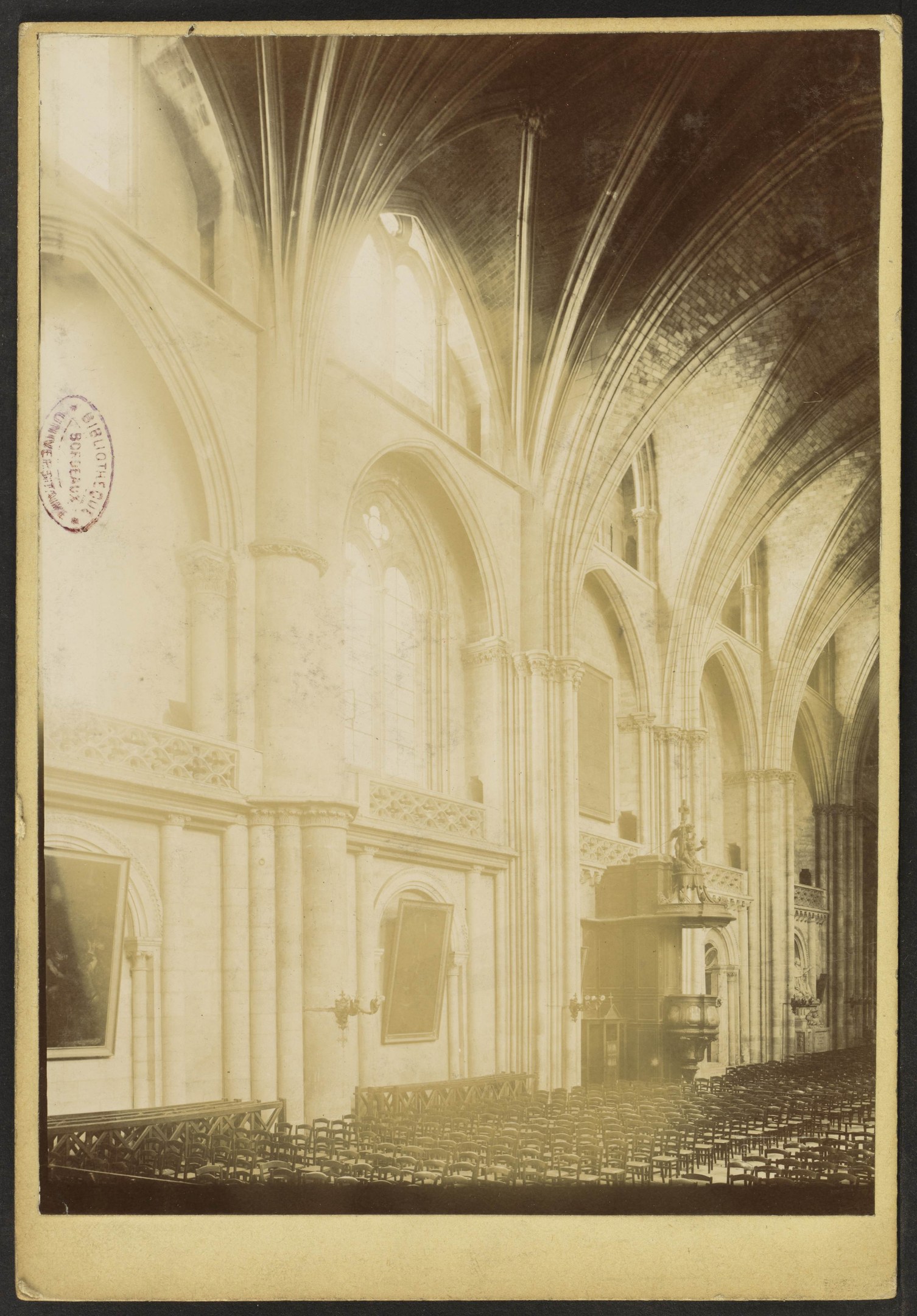 Alte Fotografie eines Kircheninneren mit Bögen, Säulen, Rahmen an den Wänden und einer Decke, mit verstreuten Objekten, die Pracht und historische Bedeutung vermitteln.