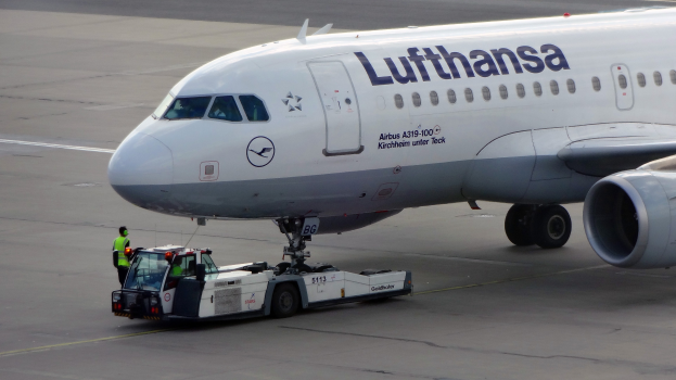 Ein Lufthansa Airbus A319-100 steht auf der Startbahn am Frankfurter Airport, mit einem Fahrzeug und einer Person in der Nähe, bereit zum Abflug.