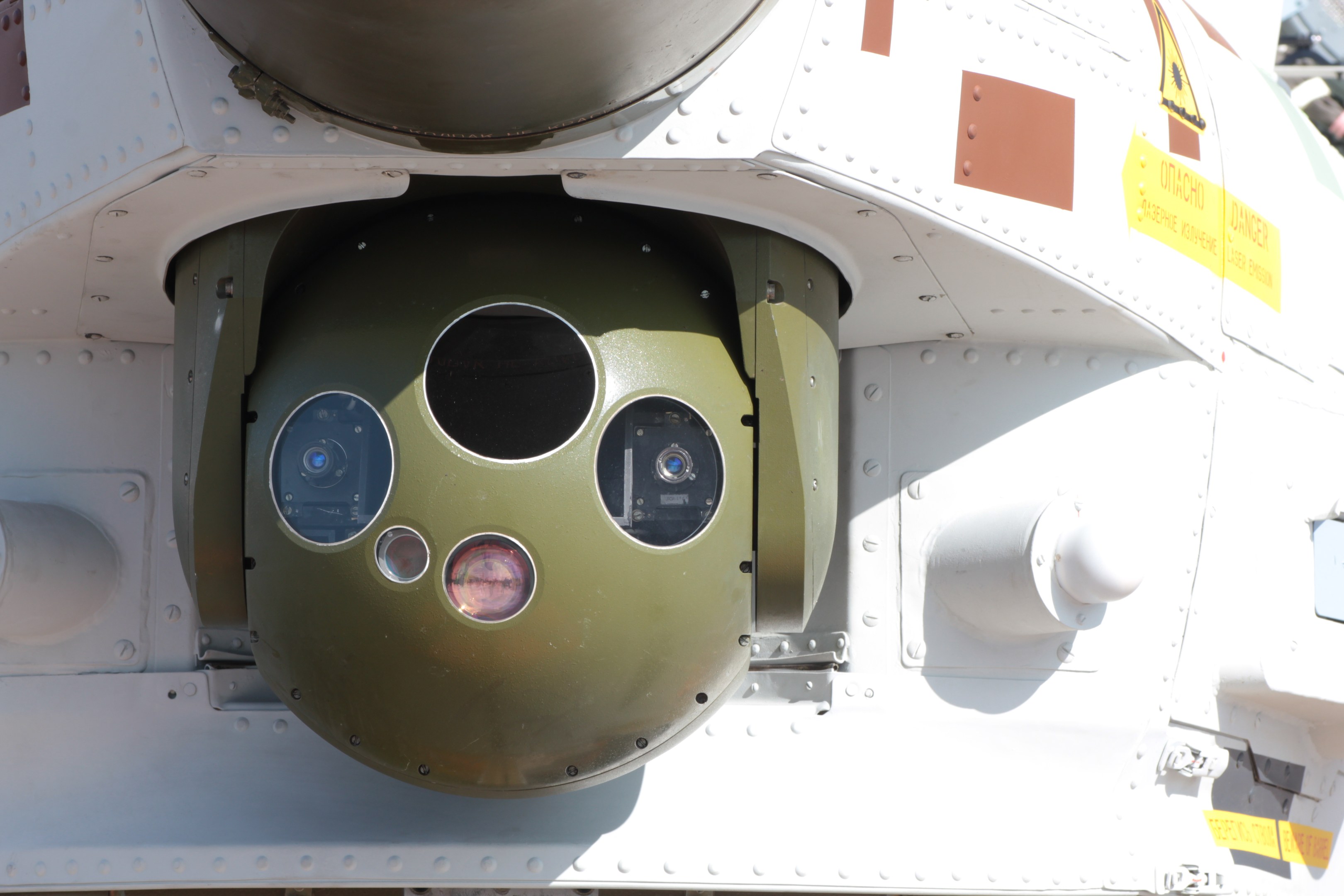 Nahaufnahme eines Militärfahrzeugs mit einer runden, grün-weißen Rakete, die seitlich an einem Metallrahmen befestigt ist.