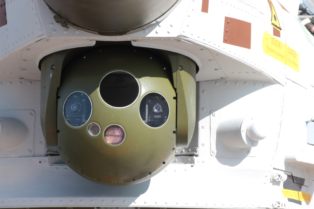 Nahaufnahme eines Militärfahrzeugs mit einer runden, grün-weißen Rakete, die seitlich an einem Metallrahmen befestigt ist.
