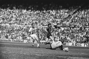 Schwarzes und weißes Foto von Fußballspielern im Einsatz auf einem Feld mit Zuschauern im Hintergrund und einer Bundesliga 1978-79 Ajax 1-1 Hannover 96-Tafel.