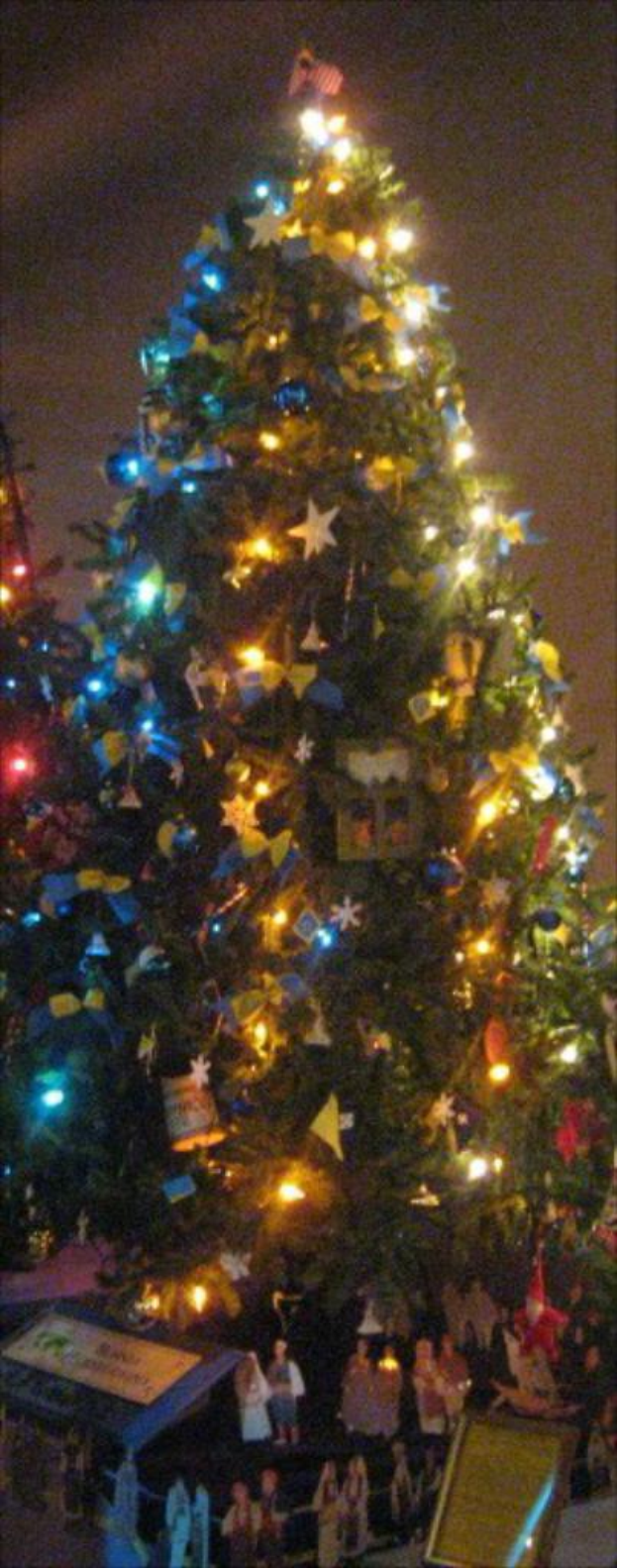 Ein geschmückter Weihnachtsbaum mit Statuen von Menschen auf einem darunter liegenden Tisch.