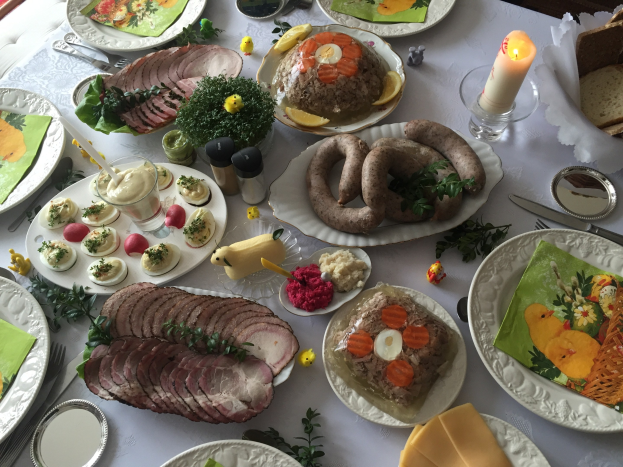 Ein langer Tisch mit verschiedenen Speisen, Besteck und Kerzen, umgeben von Stühlen, das typische Bild eines traditionellen deutschen Osteressens.