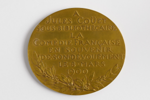 Goldmedaille mit einem Lorbeerkranz und der Inschrift "A Jules Couet Sous Bibliothèque" vor einem weißen Hintergrund.
