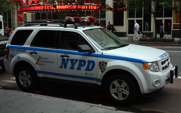 Ein weißes Auto steht am Straßenrand mit Geschäften im Hintergrund, die Glasdoors haben.