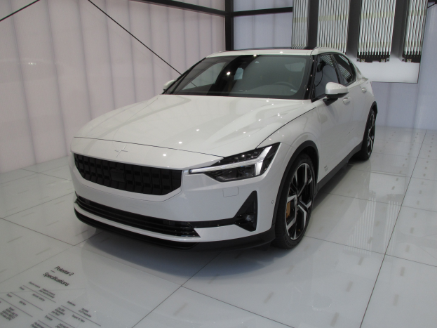 Weißer Polestar 1 Elektroauto in einer Ausstellung mit einem schlanken, modernen Design, glänzender Lackierung, hellen, winkligen Scheinwerfern, langer Motorhaube, niedrigem Körper, großen Sporträdern, geräumigem, ledernen Innenraum und modernem Armaturenbrett.