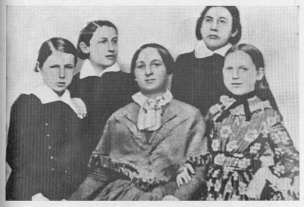 Schwarzes und weißes Foto einer vielfältigen Gruppe von Frauen, mit einer sitzend in der Mitte, verbunden mit dem Text "Die Frauenwahlrechtsbewegung" unten.