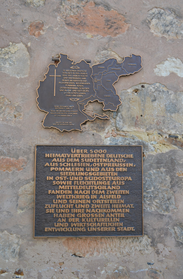 Metallplatte an einer Steinmauer mit einer Deutschlandkarte und eingraviertem Text über das Gebiet.