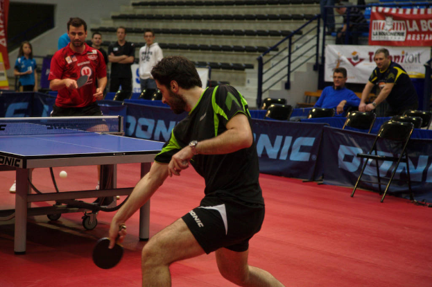 Eine Gruppe von Menschen in verschiedenen Farben, darunter schwarz, weiß und blau, versammelte sich um einen Tisch mit einem Spiel, Stühlen und einer Treppe im Hintergrund.