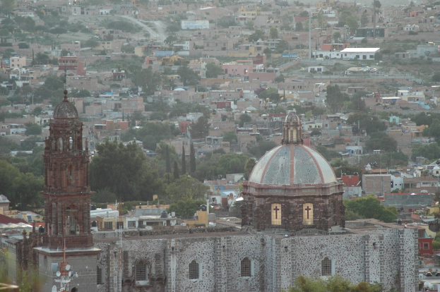 Eine Luftaufnahme einer Stadt mit Bäumen, Gebäuden, Straßen, Polen und einer Kirche im Vordergrund.