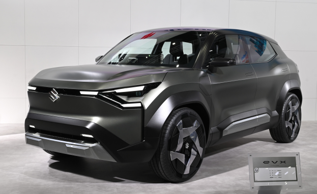 Ein elegantes, modernes Suzuki EVX Concept-Auto mit glänzender schwarzer Lackierung, großem Kühlergrill und geschwungener Motorhaube auf der IAA in Frankfurt, mit einer Tafel im Vordergrund und einer Wand im Hintergrund.