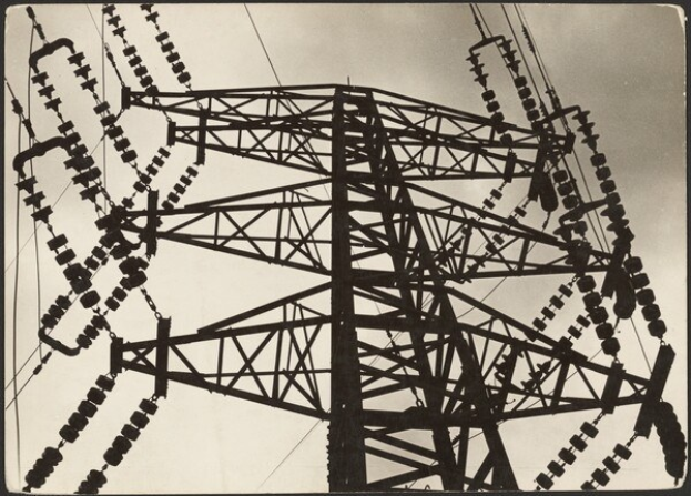 Schwarz-weiß-Foto eines Hochspannungsmastes mit Drähten vor einem Himmel, mit Text unten.