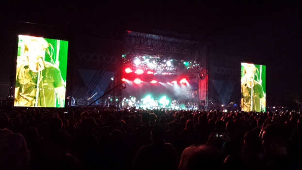 Ein Konzertbild mit einer Menge unten, einem Bildschirm links und einem weiteren Bildschirm rechts.