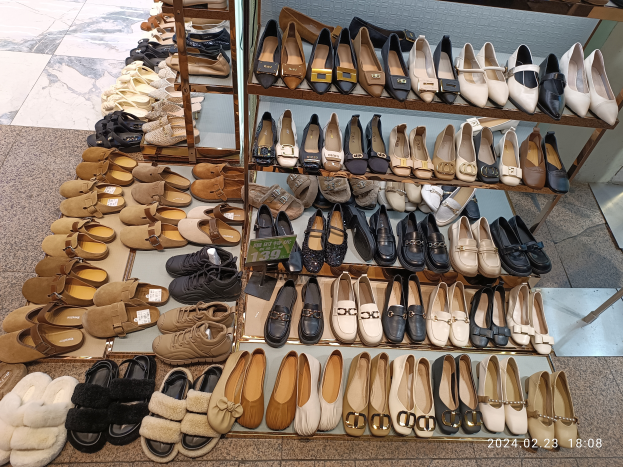 Ein Schaufenster voller verschiedener Schuharten, die auf Ständern angeordnet sind, jeweils mit einem Preisschild versehen.