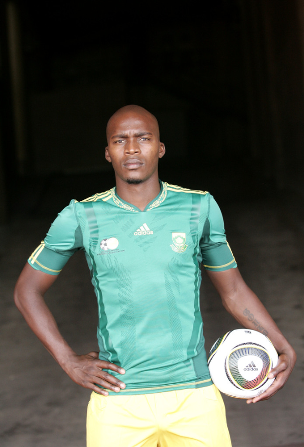 Ein Mann in einem Füßtballtrikot, der einen Füßtball in der Hand hält.