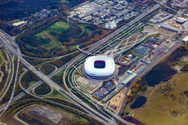 Luftaufnahme des Olympiagel"ndes in Munich, Deutschland, umgeben von Geb"uden, B"umen, Stra"en, Fahrzeugen und Gras.