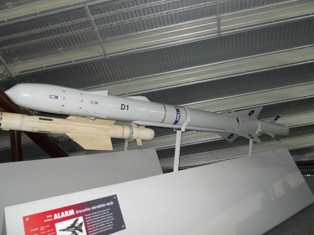 Raketen werden mit einer weißen Tafel am Boden gezeigt, die ein rotes und graues Plakat mit Text auf der linken Seite und ein weißes Dach oben hat.