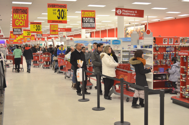 Ein volles Walmart mit Einkaufstaschen tragenden Kunden und Einkaufswagen, umgeben von Warenpräsentationen, Schildern und Deckenleuchten.