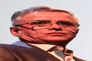 Ein Mann im Blazer, Krawatte und Brille steht vor einem weißen Hintergrund und wird als CEO der Bank of England identifiziert.