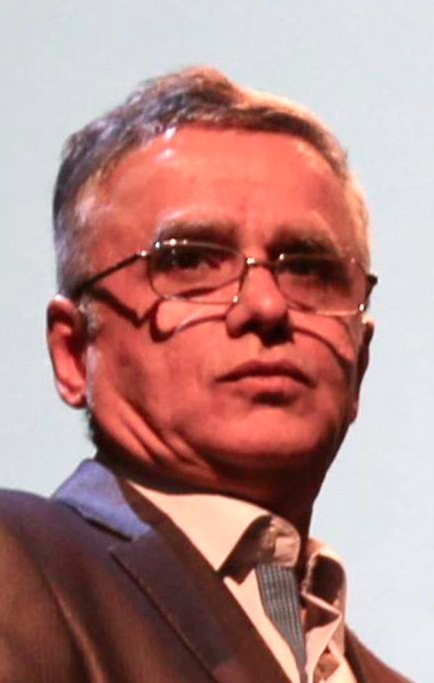 Ein Mann im Blazer, Krawatte und Brille steht vor einem weißen Hintergrund und wird als CEO der Bank of England identifiziert.