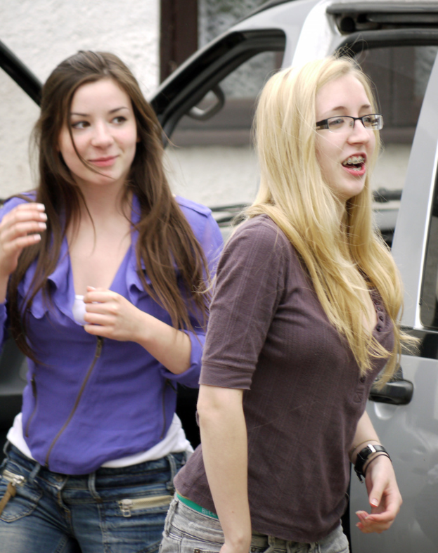 Frauen, die auf einem Boden mit einem Auto, einer Wand und einem Fenster im Hintergrund stehen.