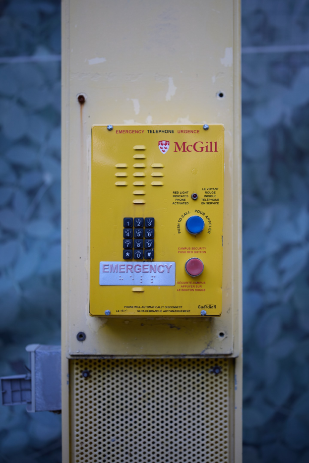 Gelber Notruf an einer Gebäudewand mit Tasten und Text montiert.