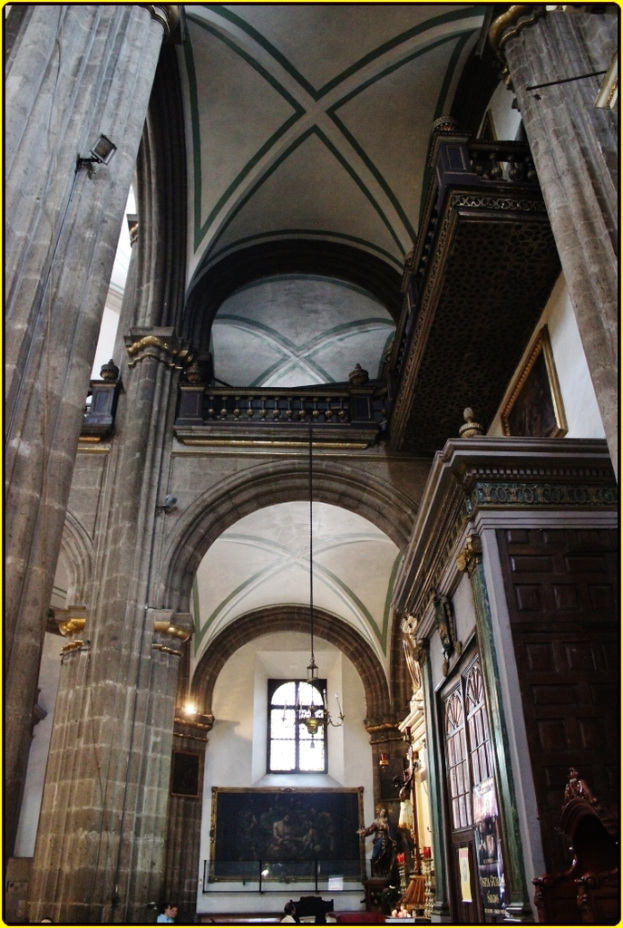 Ein Innenblick in einen Palast mit Schränken, beleuchteten Säulen, Wandskulpturen, einem großen Rahmen und einer Deckenlampe.