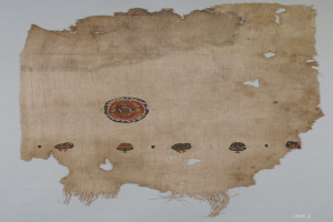 Ein Stück Stoff mit einem lebendigen, detaillierten kreisförmigen Design, das verschiedene geometrische Formen und Farben auf einem weißen Hintergrund zeigt.