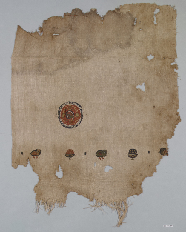 Ein Stück Stoff mit einem lebendigen, detaillierten kreisförmigen Design, das verschiedene geometrische Formen und Farben auf einem weißen Hintergrund zeigt.