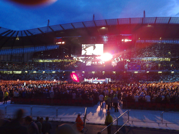 Eine Veranstaltungslocation mit Menschen, Scheinwerfern und einem Projektionsschirm.